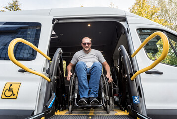 A man in a wheelchair on a lift of a vehicle for people with disabilities
