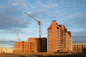 Multi-story complex of houses, construction is underway, cranes are working, construction in progress