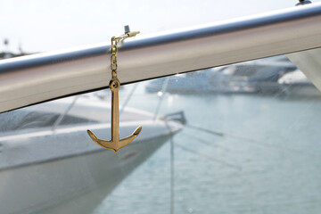 Sea golden anchor on the background of blured yachts in the sea