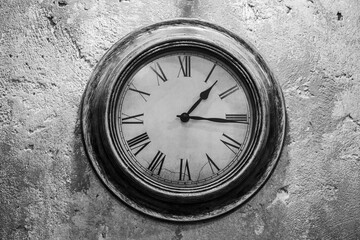 Ancient clock on an old cement wall background. Black and white