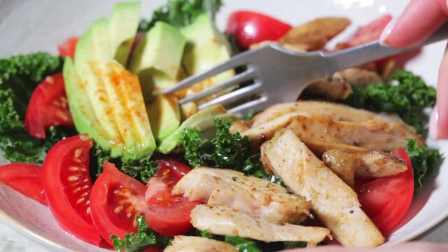 Chicken salad with tomato, avocado and kale in gray bowl. Diet food concept.