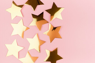 New Year festive abstract background with golden sparkle stars  on pastel pink background, flat lay, border.