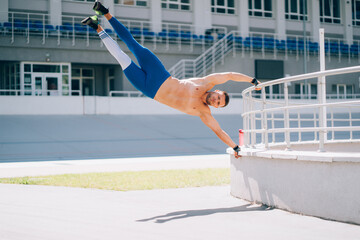 Young athletic man performs gymnastic elements - human flag.