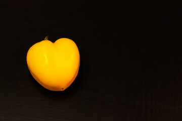 Heart shaped yellow pepper on black background