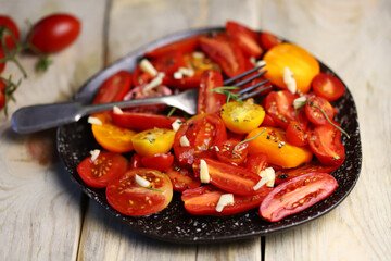 Selective focus. Rustic tomato salad with garlic and olive oil. Salad from different varieties of tomatoes.
