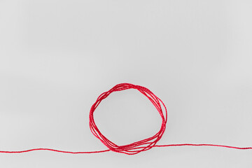a red silk thread looped in a circle form, extending on both ends, symbolizing the red thread of...