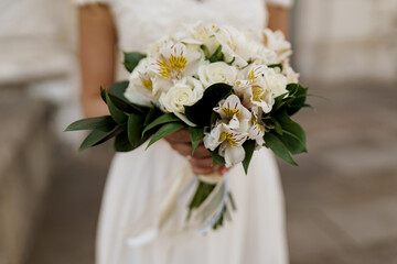 Wedding bouquet with white roses and green leaves. Bride in dress holds bouquet. Advert for wedding agency.
