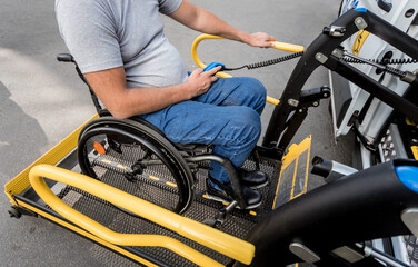 A man in a wheelchair on a lift of a vehicle for people with disabilities