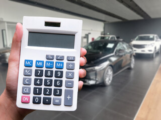 Hand man pressing calculator for business finance on car showroom blurry background for automotive or transportation