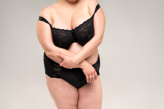 Fat woman with big natural breasts in a lace lingerie on gray background