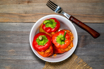 red pepper stuffed with meat and bulgur in a white plate on a wooden table