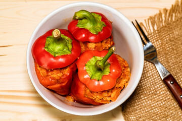 red pepper stuffed with meat and bulgur in a white plate on a wooden table