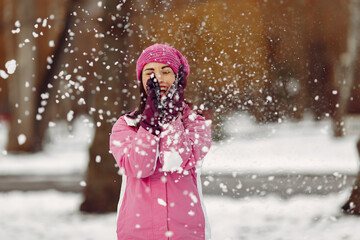 Woman in a winter park. Lady in pink sportsuit.