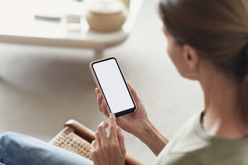 Young woman using smart phone at home, white blank empty screen. Girl texting on mobile phone indoor.  Connection, technology, apps, smartphone mock up, communication concept