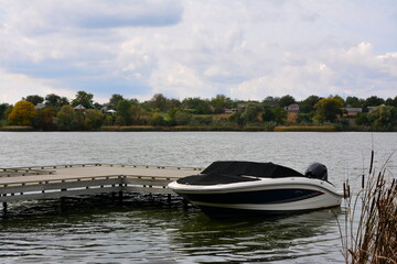 Fototapeta premium A motor boat at the pier on the bank of a small river.
