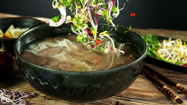 Super Slow Motion Shot of Ingredients Falling into Beef Pho Soup at 1000 fps.
