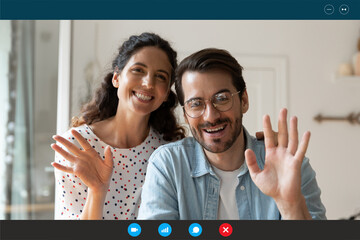 Head shot portrait computer screen view happy young couple waving hands, looking at camera, smiling wife and husband greeting friends or relatives, talking, chatting online, using webcam at home