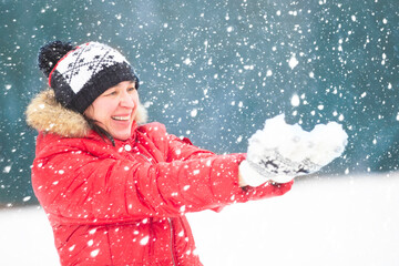 Adult woman in bright clothes holds snow. People in snowy winter.