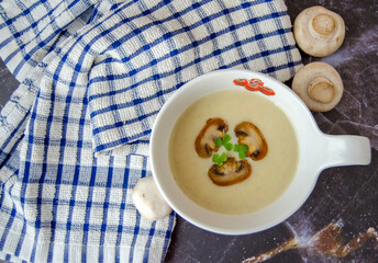 Mushroom cream soup close-up. Champignon soup puree, pie and champignon on a dark granite background. Tasty winter vegetarian food.