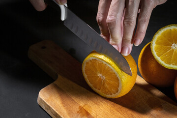 Hands of unrecognizable woman cutting fresh orange slices