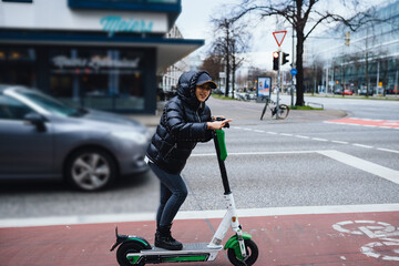 Beautiful young woman riding an electric scooter, street-style