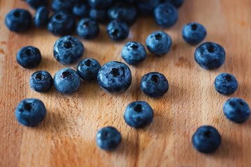 On the wooden kitchen board are washed ripe large berries of wild blueberries, which were recently collected in the forest. A rich harvest of berries.