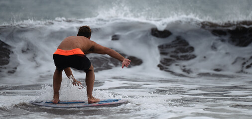 View of a surfer in surfing his board or skimboarding in shallow water