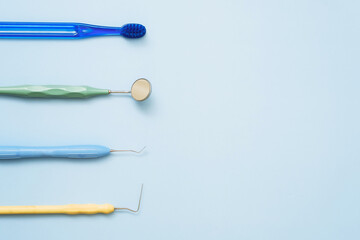 Toothbrush and mirror, tweezers and probe for dental treatment on a blue background. Flat lay, copyspace