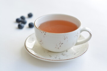A white ceramic cup of friut tea on white background. Blueberries.