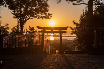 赤い夕日に照らされた鳥居と長く伸びる影（横構図）