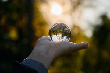 Hand held lensball in autumn forest. Selective focus with shallow depth of field.