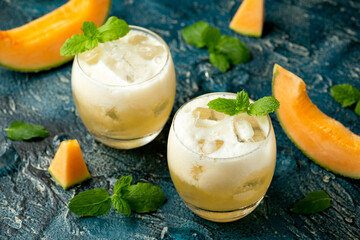 Refreshing Cantaloupe Melon cocktail with ice and mint on rustic table