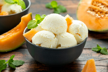 Melon ice cream with mint in bowl on wooden table