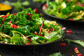 Tenderstem broccoli and egg noodles Asian style vegetarian salad with roasted pine nuts and pomegranate seeds