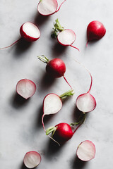 Cutted fresh radish on a white marble kitchen board. Preparation food cooking concept.