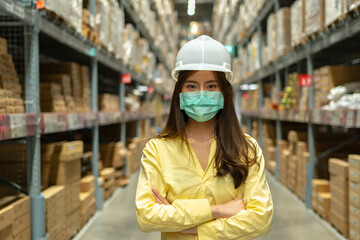 Female warehouse worker inspecting a warehouse in a factory. Wear a safety helmet and mask for working safety. Concept of warehouse.