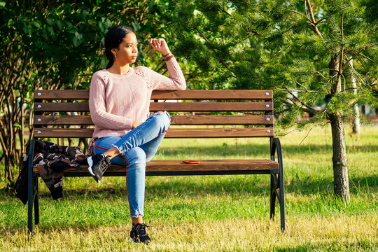 Vietnamese woman in pink sweater sitting on the bench