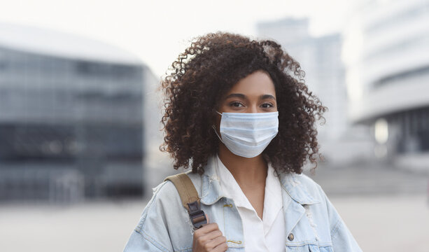 Young woman wearing protective face mask in a city, Masked african teenage student girl on a city street,  Epidemic, pandemic, corona virus protection, healthy lifestyle, people concept