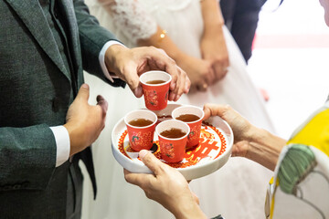 Bridegroom holding tea to serve elderly during Chinese wedding tea ceremony. Chinese word on tray...