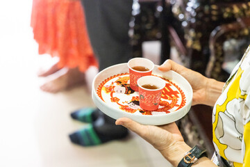 Person holding tray with two cups of tea in disposable cup in Chinese wedding ceremony.  Chinese...