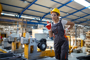 Female factory worker operating industrial machine in production line.
