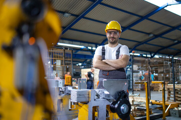 Portrait of factory worker standing by industrial machine.