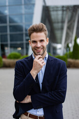 Portrait of handsome smiling man in casual wear. Successful young businessman.Young man standing on the city street near business center.