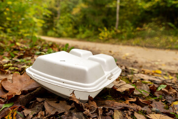 Old disposable plastic plate, box in the forest. Plastic recycling, pollution and global warming...