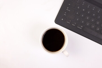 Black computer keyboard coffee cup pen on white background top view copy text space
