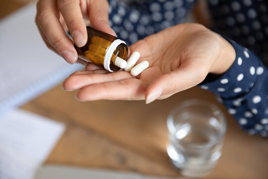 Top Above Close Up View Woman Pours Out From Bottle Pills Into Palm. Female Takes Daily Meds Complex Vitamins For Healthy Skin Nails And Hair. Effective Treatment, Remedy Pain Killer Drugs Concept