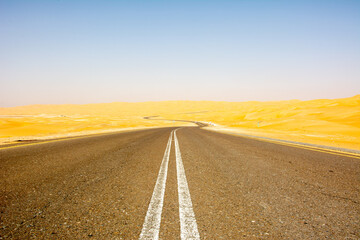 An empty asphalt road through the desert and sand dunes in the United Arab Emirates