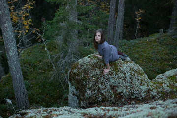 Fototapeta na wymiar Girl sits on a stone in the forest