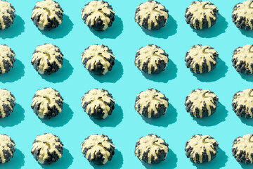 Fall pattern made of decorative pumpkins with dripping paint on a blue background. Autumn, Halloween or Thanksgiving concept. Trend shadow, flat lay, top view.