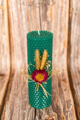 Green honey candle handmade from natural wax on a background of wooden boards. Elements from natural materials. Christmas or New Year's composition. Photo for postcards.